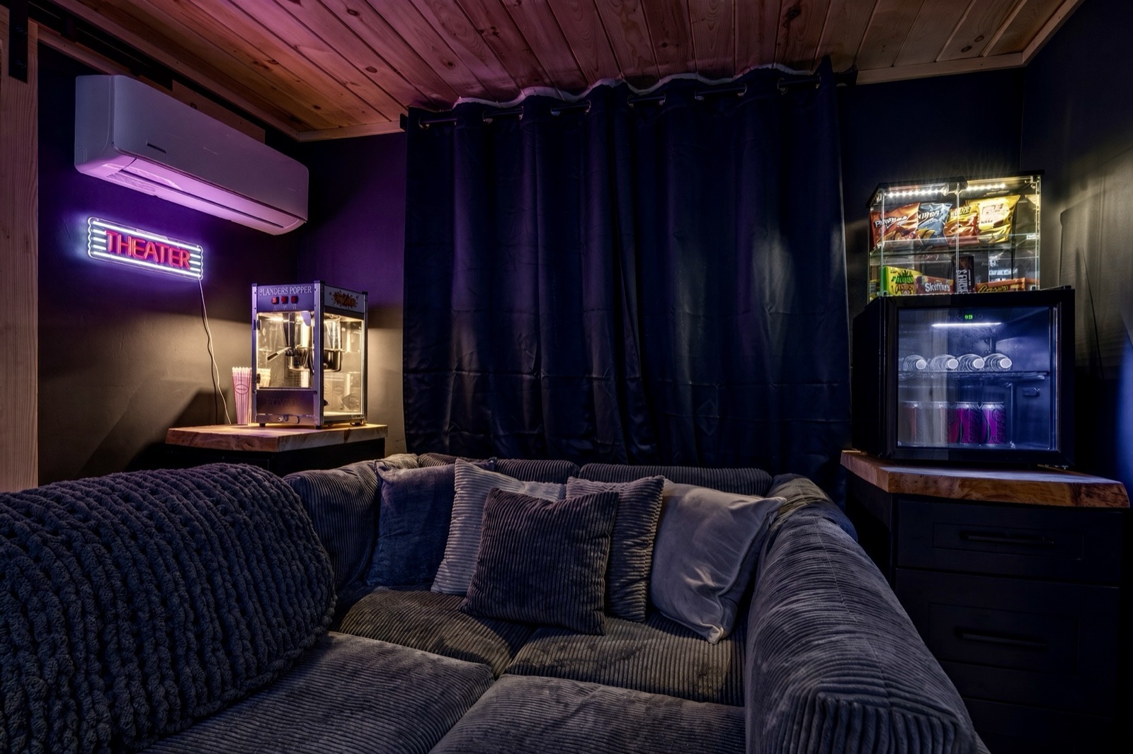 Movie theater room with velvet sofa, popcorn machine and snack fridge